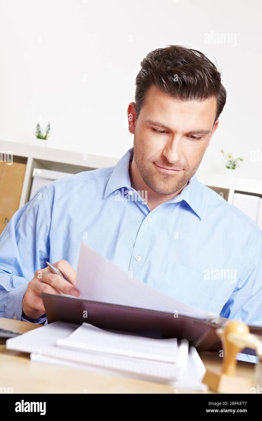 Businessman at desk attentively reads documents in office Stock Photo