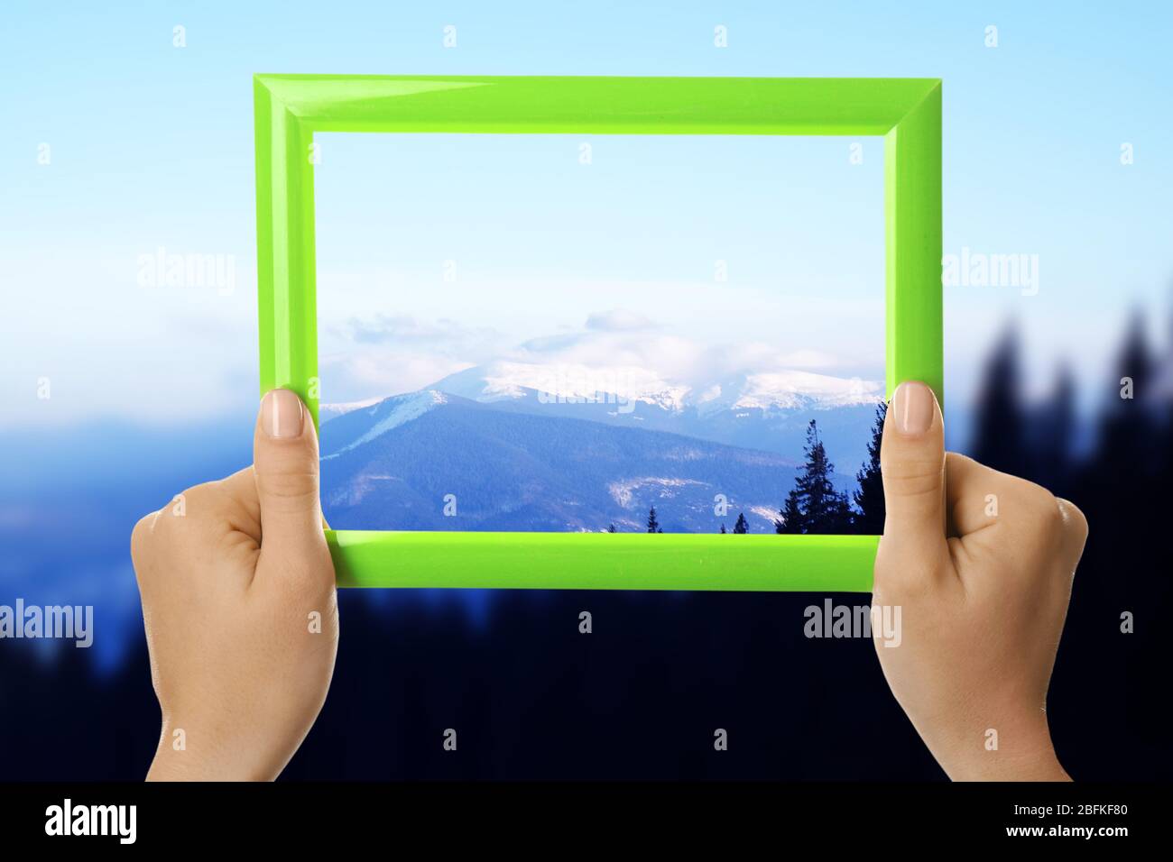 Woman hands holding empty frame on nature background Stock Photo