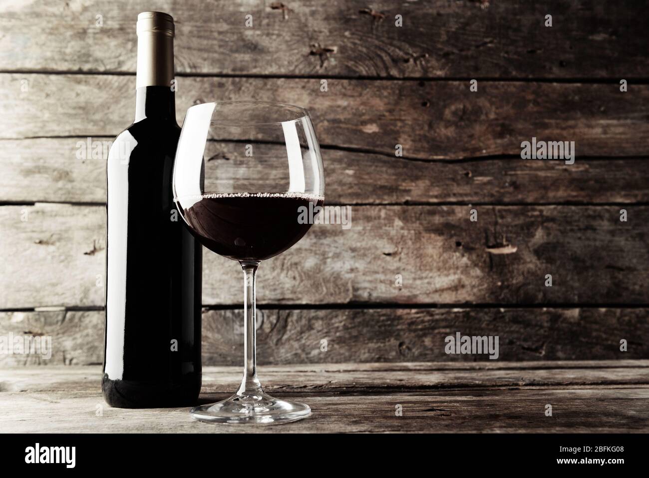 Bottle of red wine and a glass on wooden table , black and white retro ...