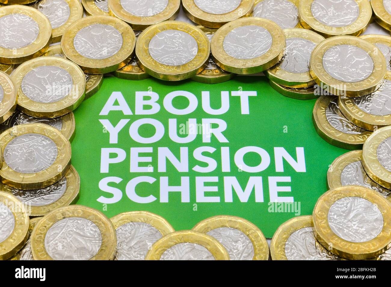 Top of a printed note with message 'About your pension scheme' surrounded by piles of British one pound coins Stock Photo