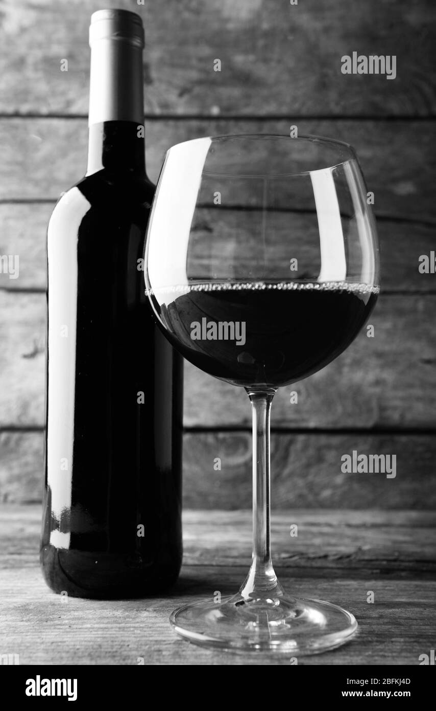Bottle of red wine and a glass on wooden table,  black and white retro stylization Stock Photo