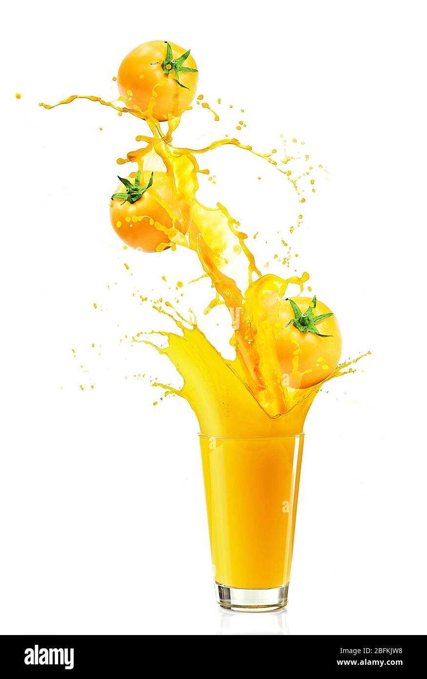 Juice splash in glass with yellow tomatoes isolated on white Stock Photo