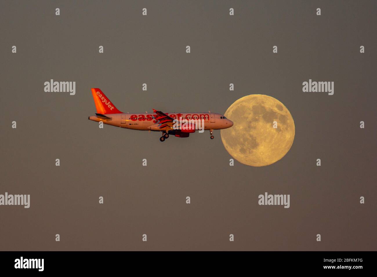 Airplane flying in front of the moon Stock Photo