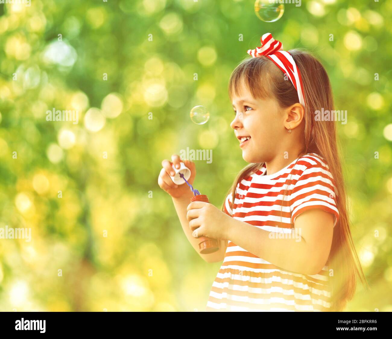 Little girl playing with bubbles in the park Stock Photo - Alamy
