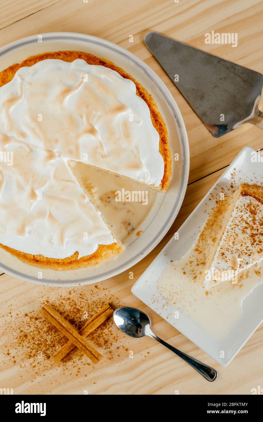 Top view of a delicious three milk cake and a little cinnamon on a pine wood background, typical Latin American dessert Stock Photo