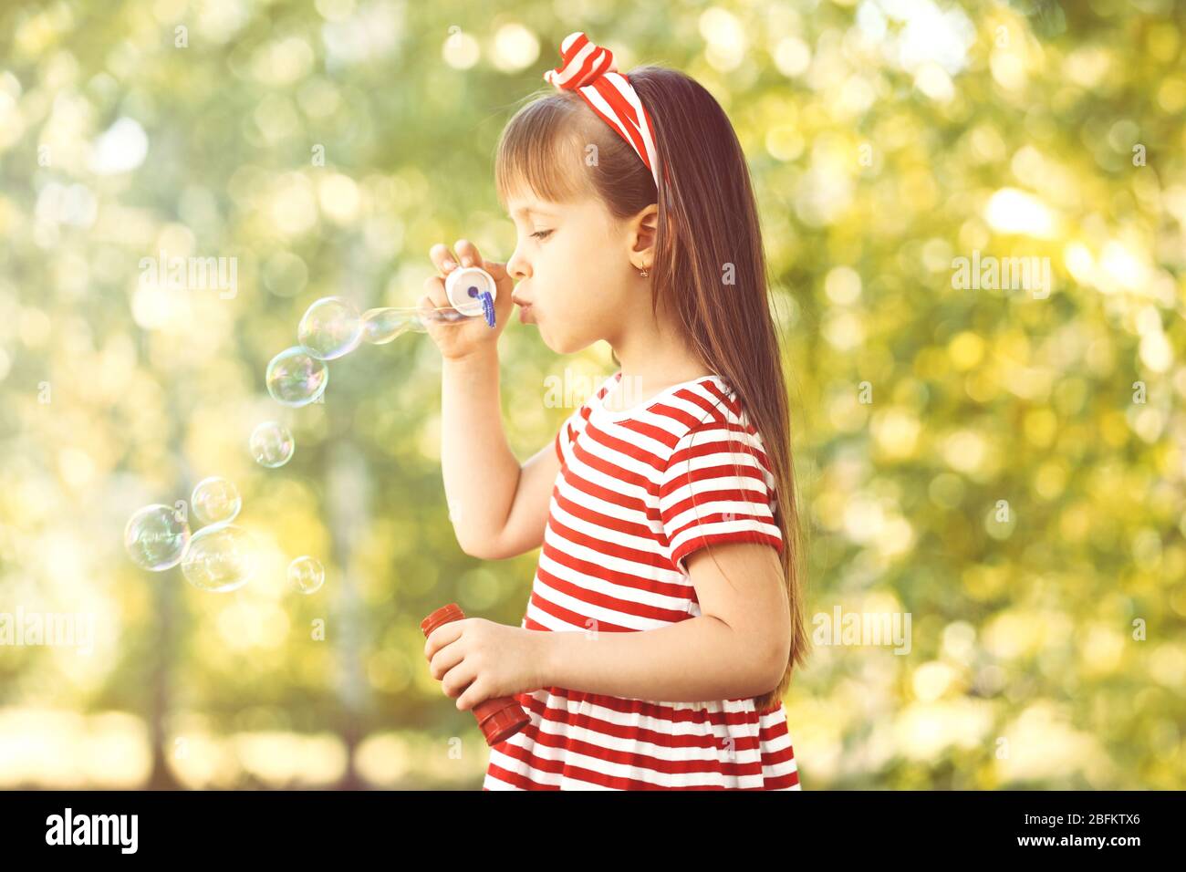 Little girl playing with bubbles in the park Stock Photo - Alamy