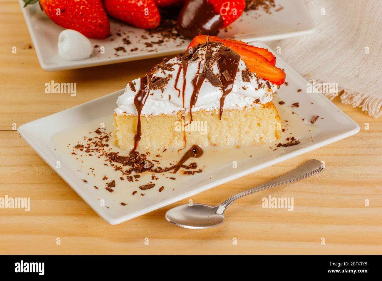 Three milk cake with chocolate syrup and some strawberries Stock Photo