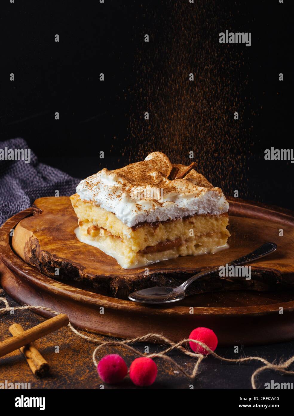 Piece of cake three milk prepared at home. The image is made on a dark background and rustic boards. Latin American dessert Stock Photo