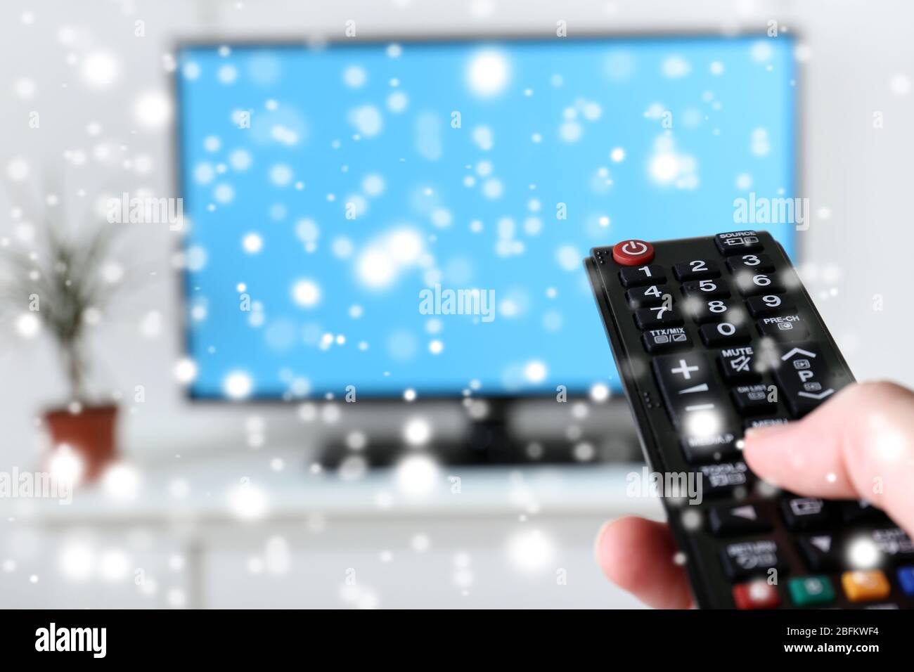 Watching TV and using remote controller over snow effect Stock Photo ...
