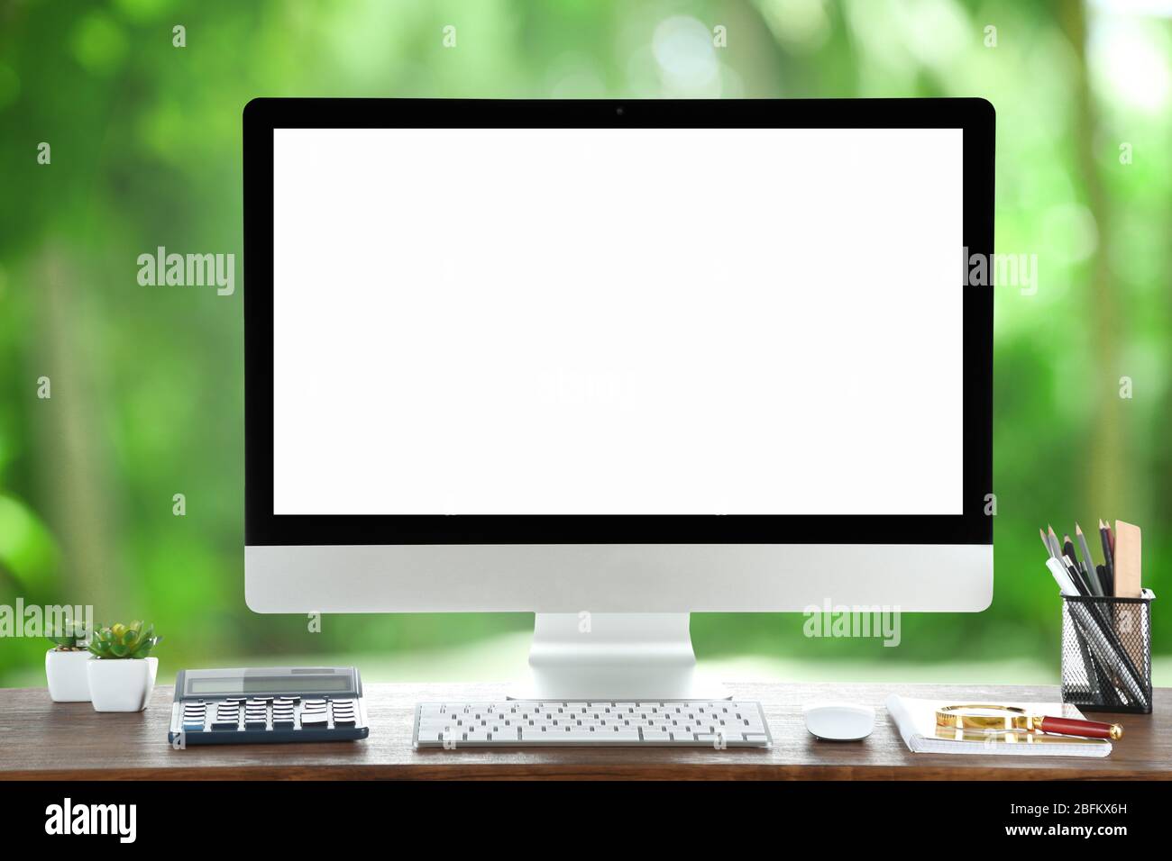 Computer on wooden table on nature green background Stock Photo - Alamy