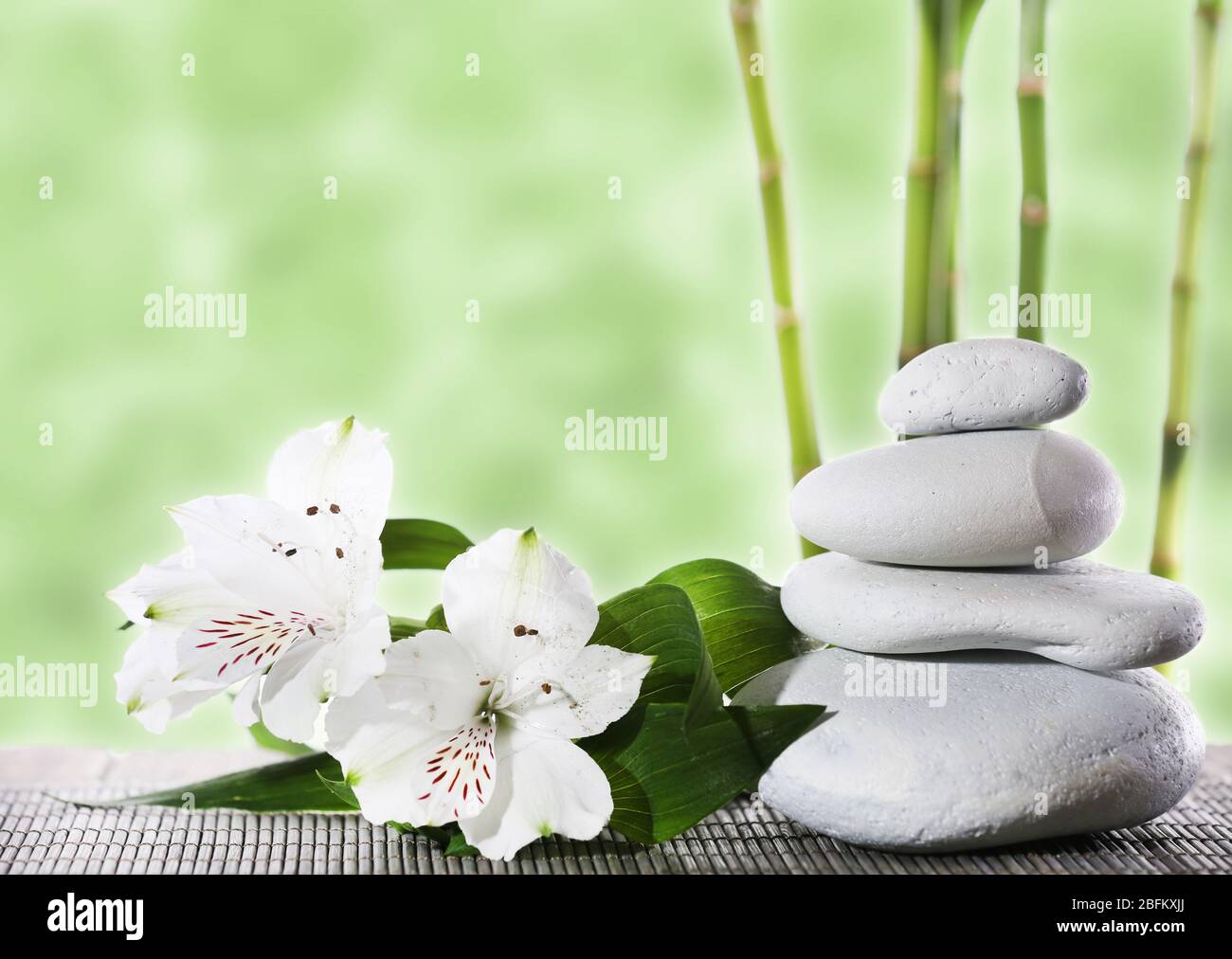 Still life of spa stones on bamboo mat surface with bamboo sticks Stock Photo