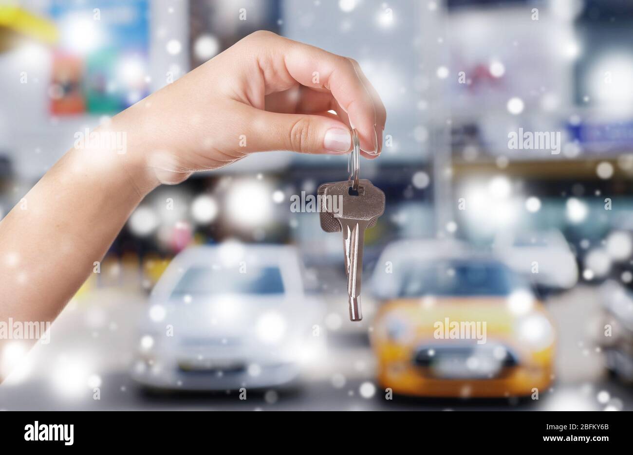 Keys in hand on blurred cars background over snow effect Stock Photo ...