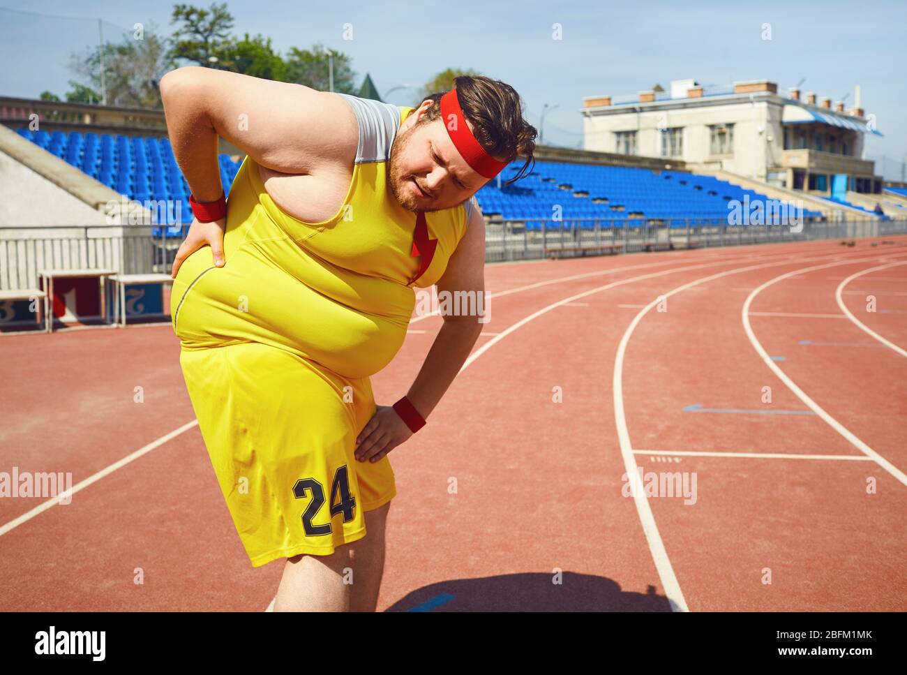 A fat man holds his back in the stadium. Stock Photo