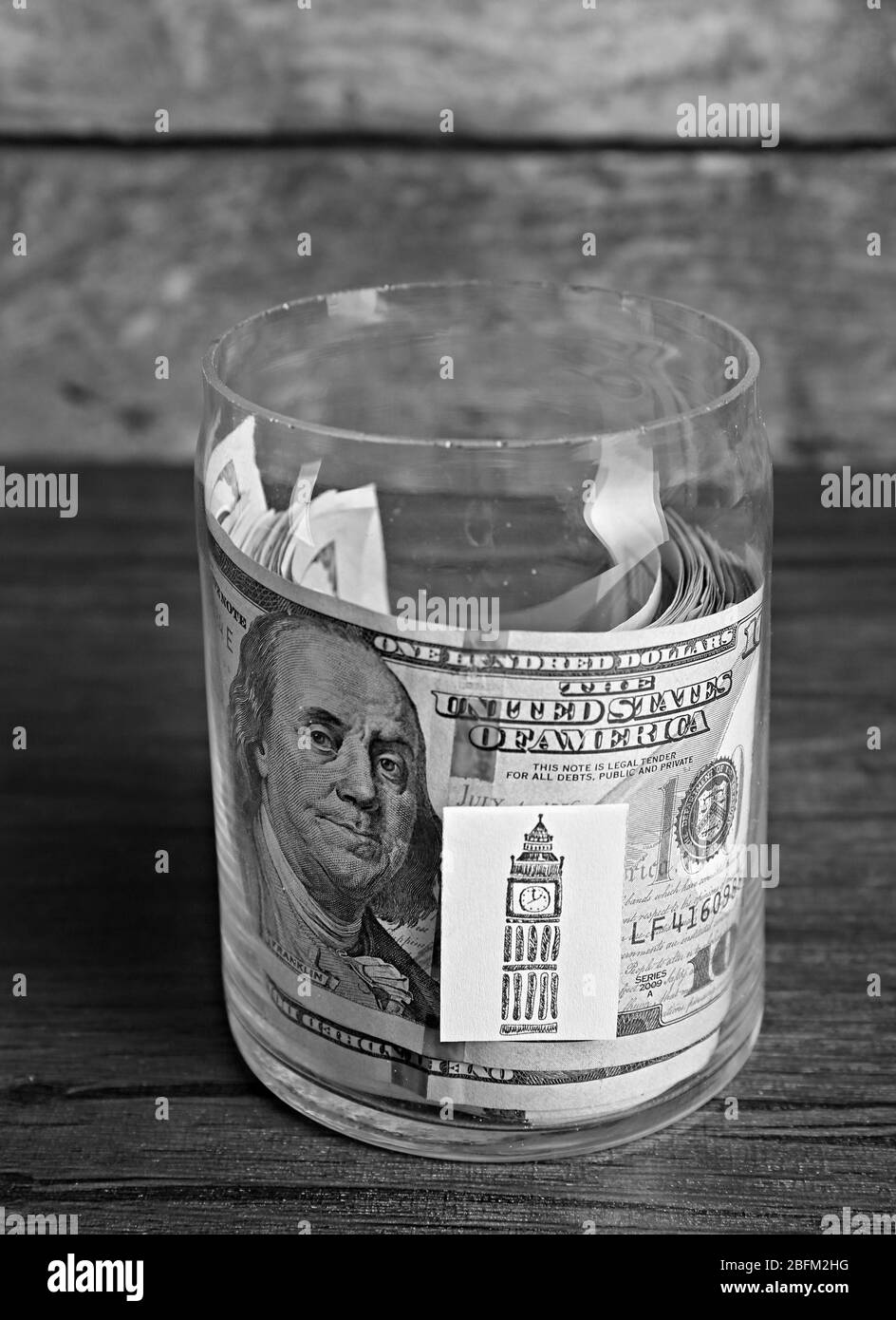 Roll of dollar banknotes for different needs in a glass jar on a table Stock Photo