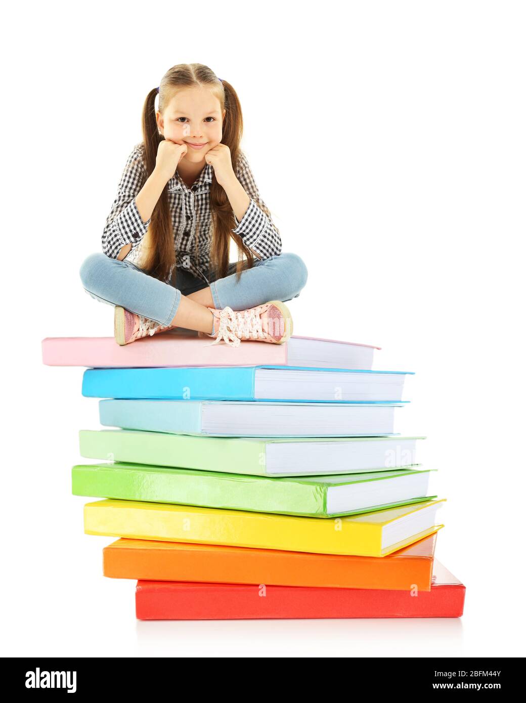 Cute little girl sitting on stack of books isolated on white Stock ...