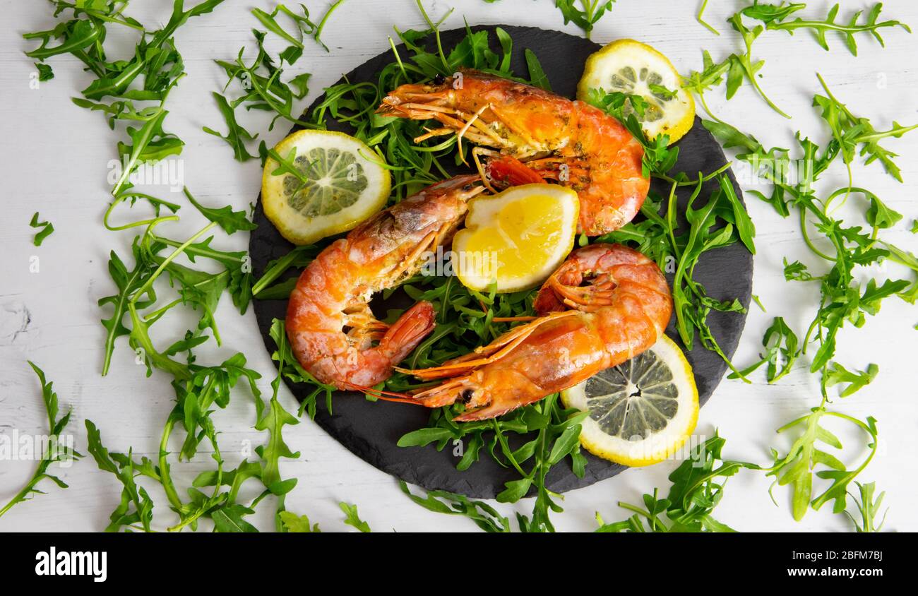 roasted prawns with lemon slices on a slate plate and white background Stock Photo