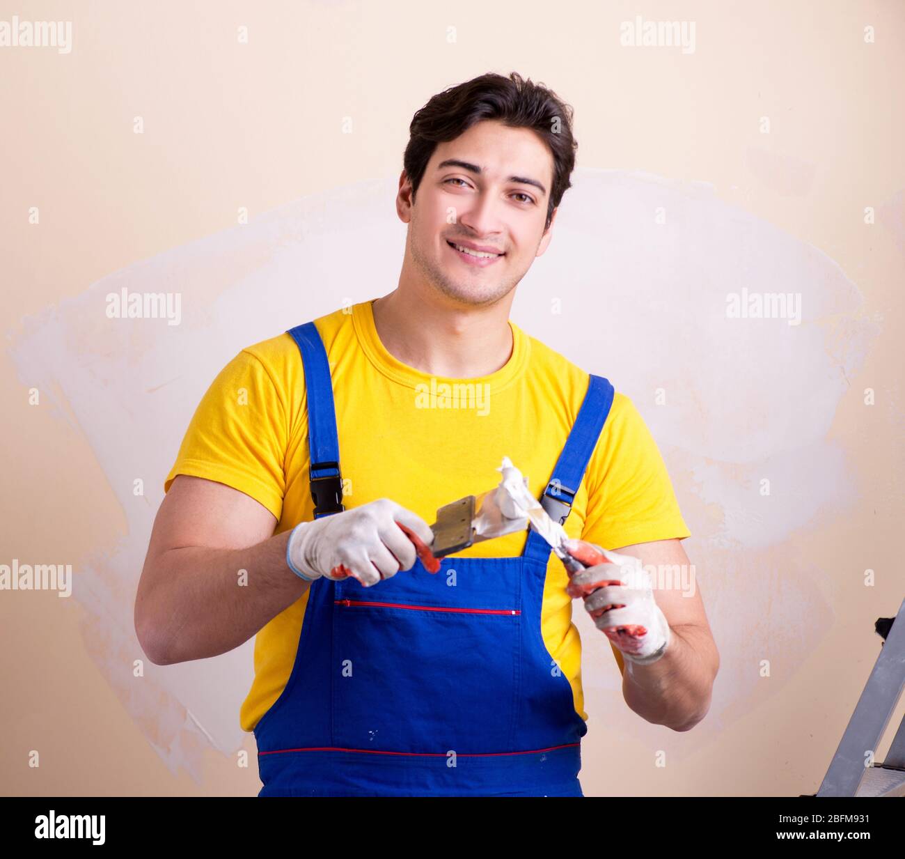 The young contractor employee applying plaster on wall Stock Photo