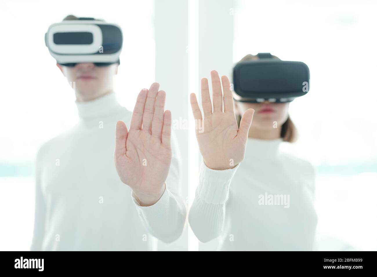 Palms of young male and female software developers in vr headsets keeping hands in front of camera while working in augmented realty Stock Photo