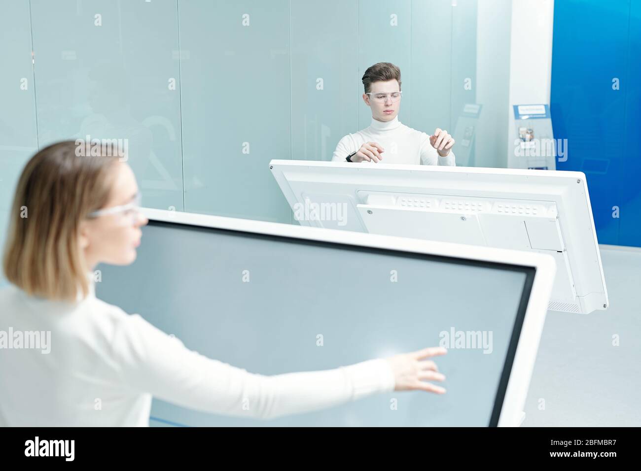 Two young progressive software developers looking through database on large interactive displays while working individually in office Stock Photo