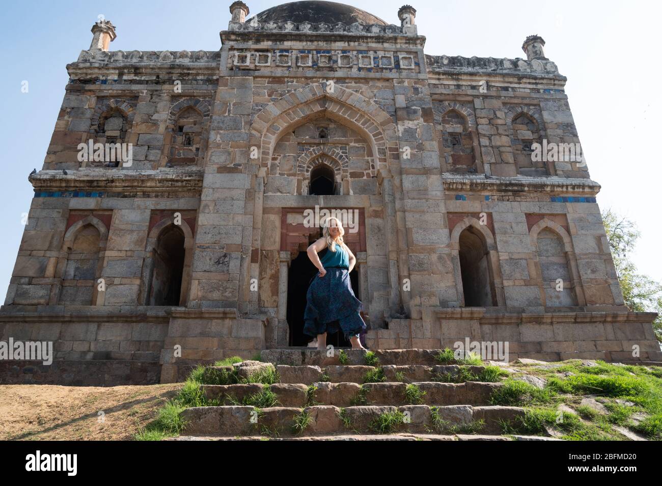 Blond tourist poses at the Tomb of Sheesh Gumbad tomb in Lodi Gardens in New Delhi, India Stock Photo