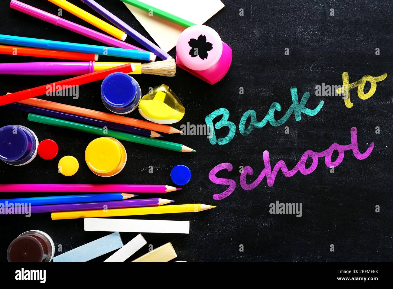Colourful stationery on blackboard background Stock Photo