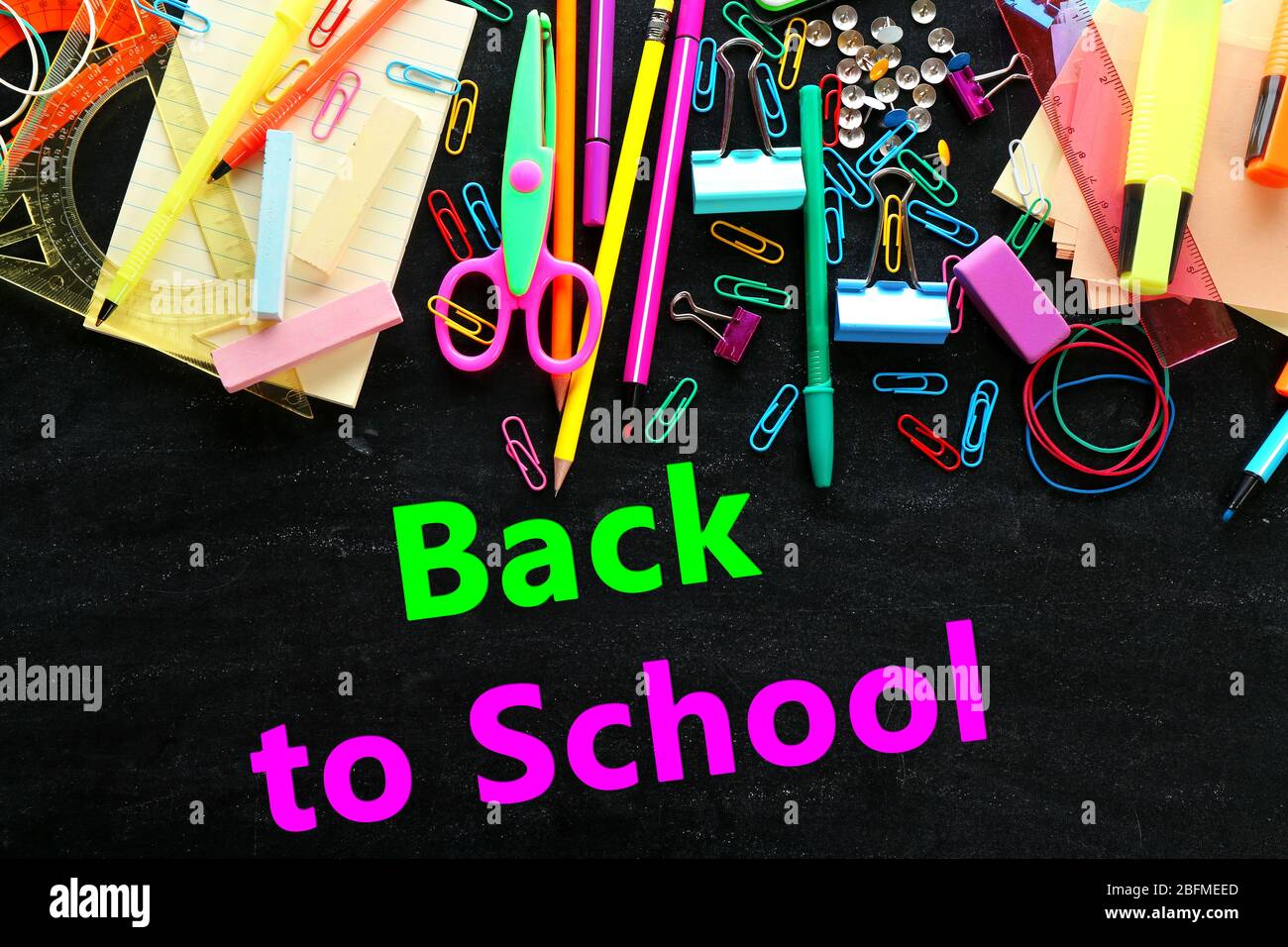 Colourful stationery on blackboard background Stock Photo