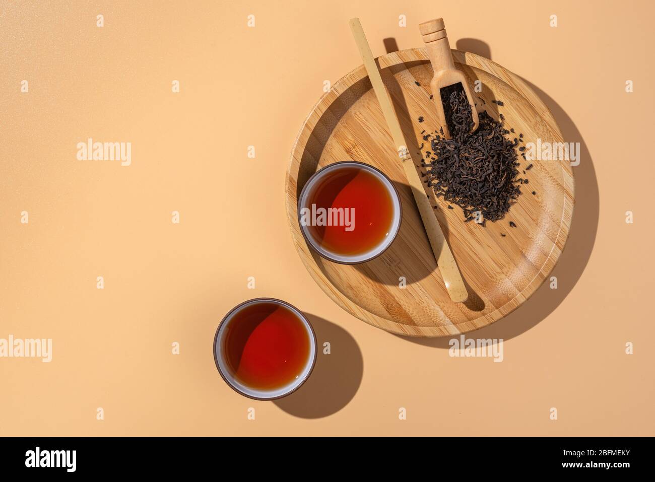 Two Ceramic Bowls With Black Puer Tea Dry Pu Erh Tea Leaves In A Wooden Bamboo Plate And Spoon On A Beige Background Stock Photo Alamy