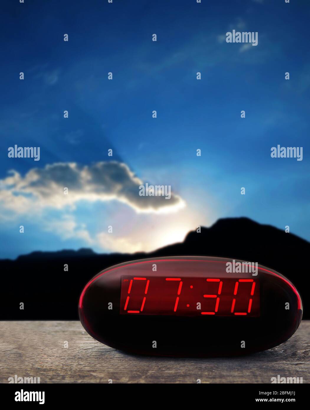 Digital clock showing 7:30 o’clock on wooden table, night background