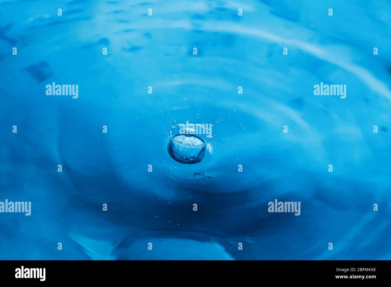 Water drops on blue surface. Water ripple background. Splashes from a drop of water. Raindrops on a blue background. The texture of the water. Aqua, Stock Photo