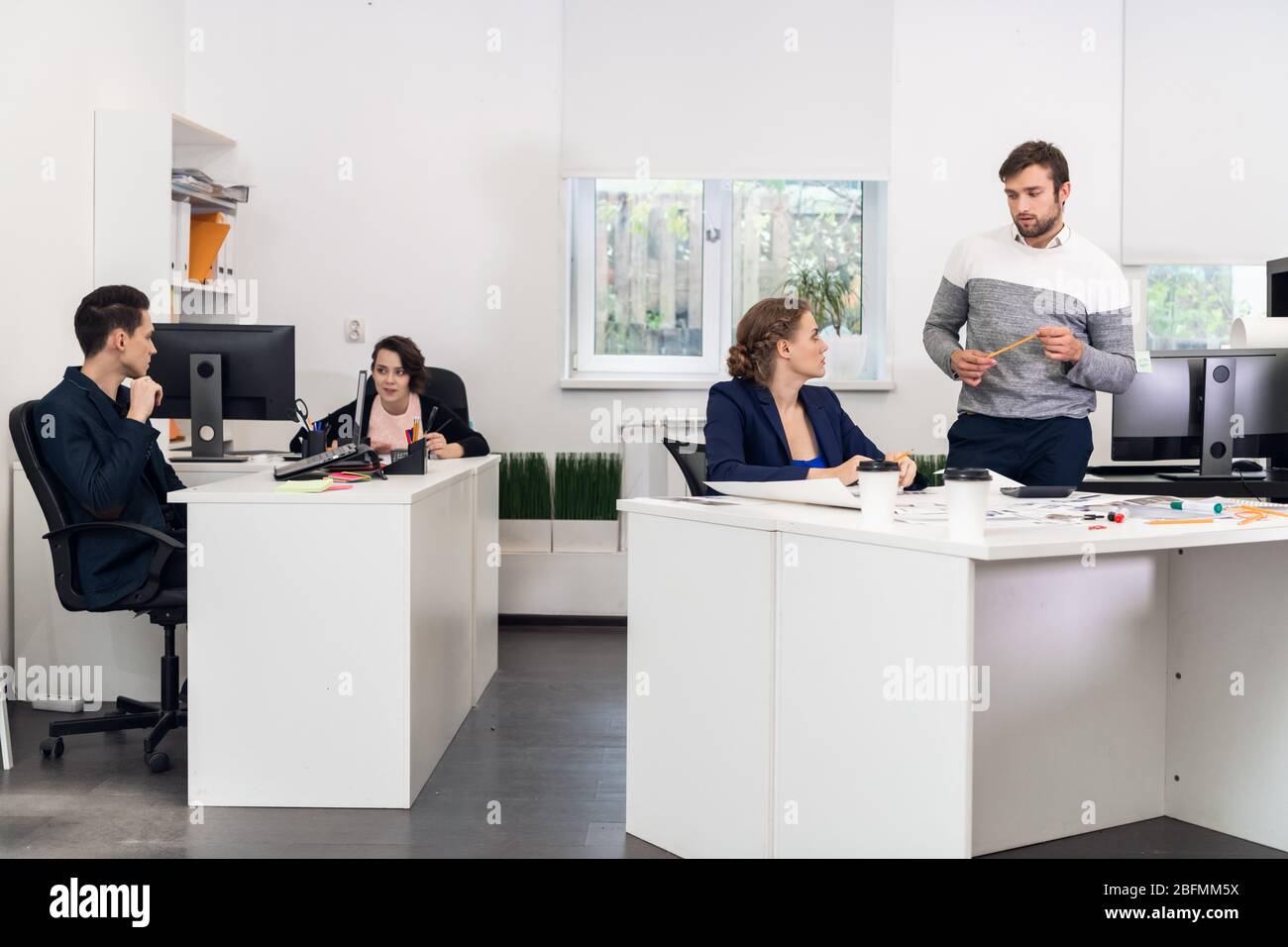 A multiracial team busy working on computers, communicating, cooperating in a coworking space. Stock Photo