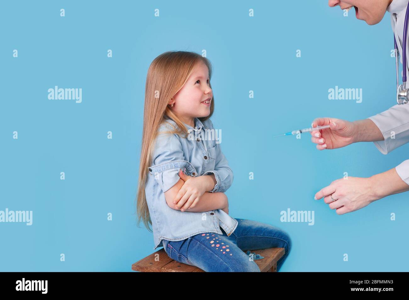 Young woman pediatrician performs a vaccination of a little girl. Stock Photo
