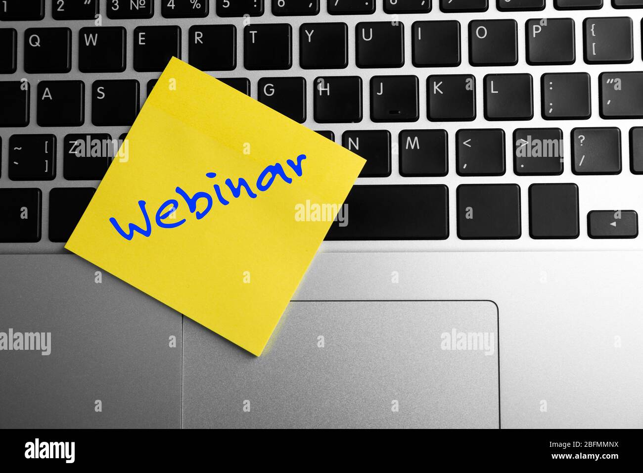 Webinar written on sticky note on laptop keyboard Stock Photo