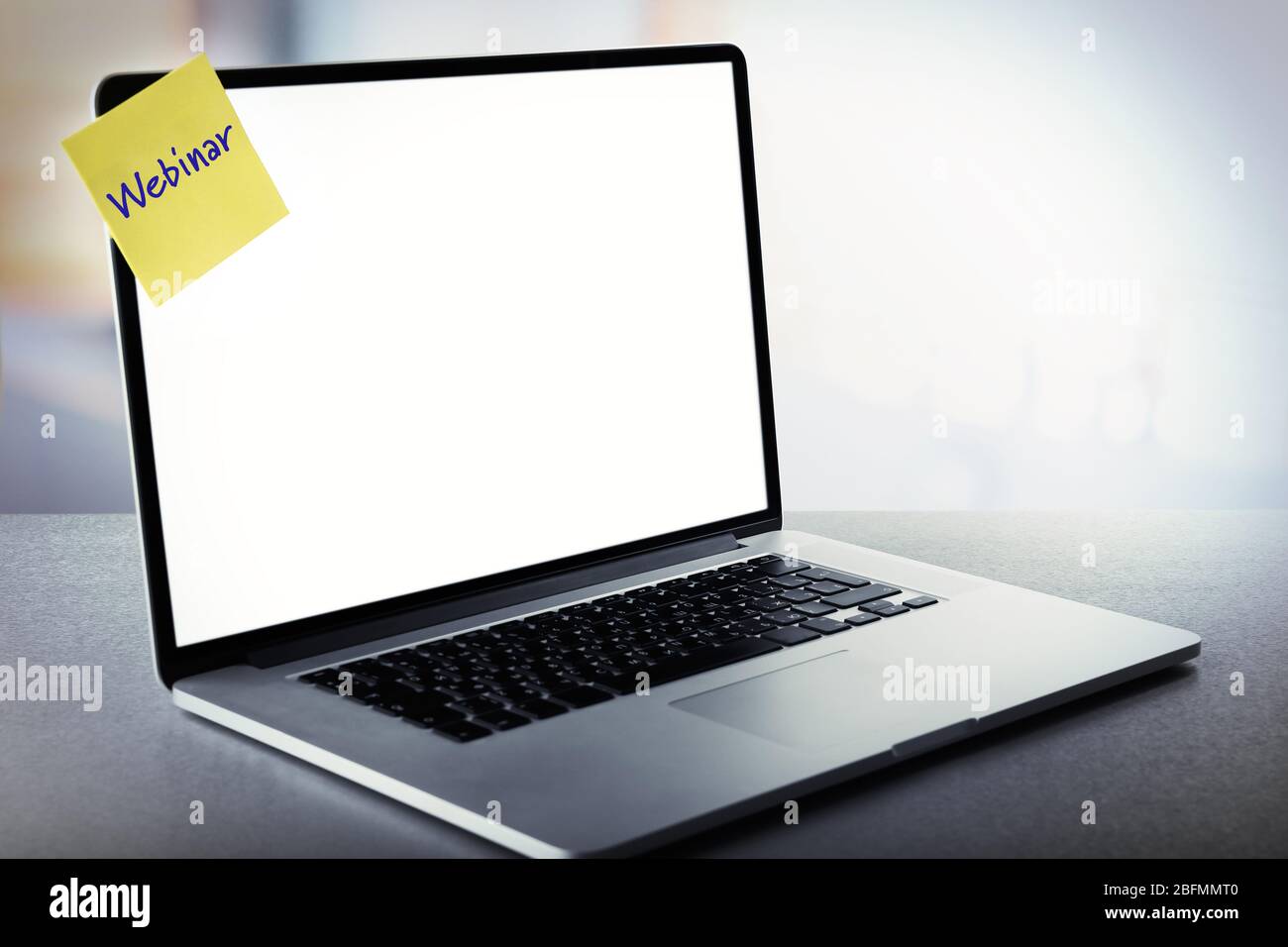 Webinar written on sticky note on laptop screen Stock Photo