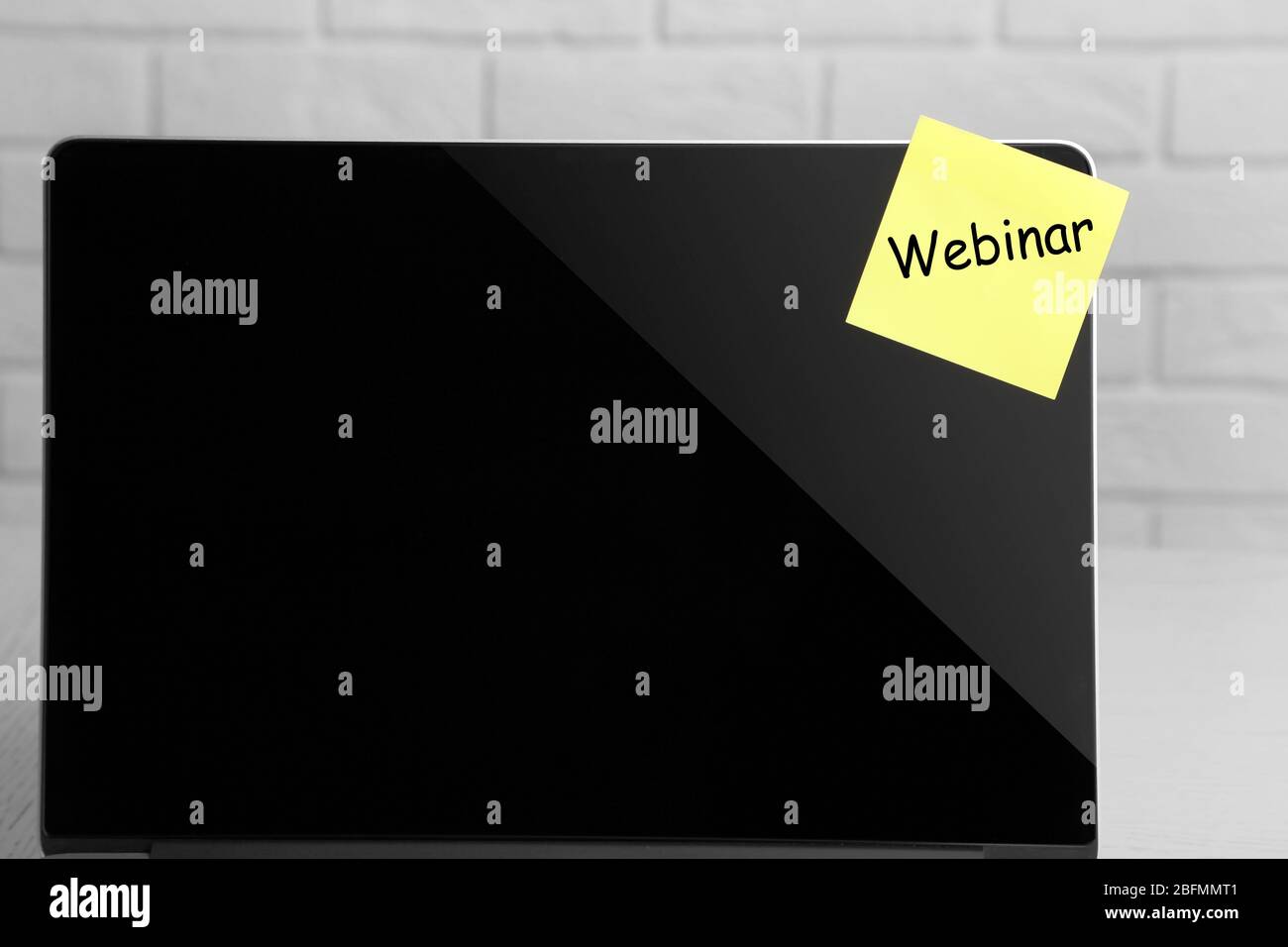 Webinar written on sticky note on laptop screen Stock Photo