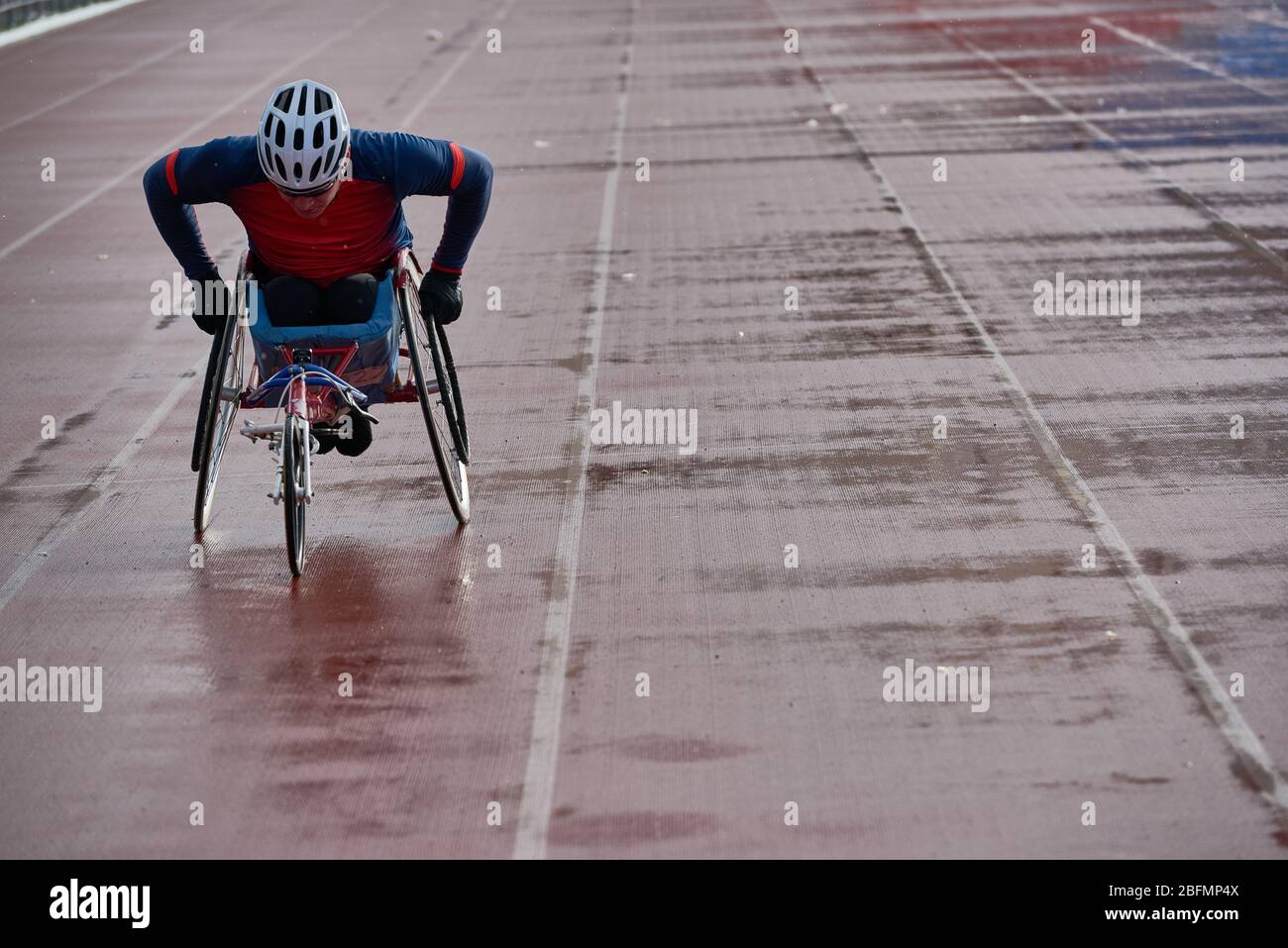 Wheelchair athletics. Strong-willed physically impaired male athlete training speed in racing chair at outdoor track and field stadium Stock Photo