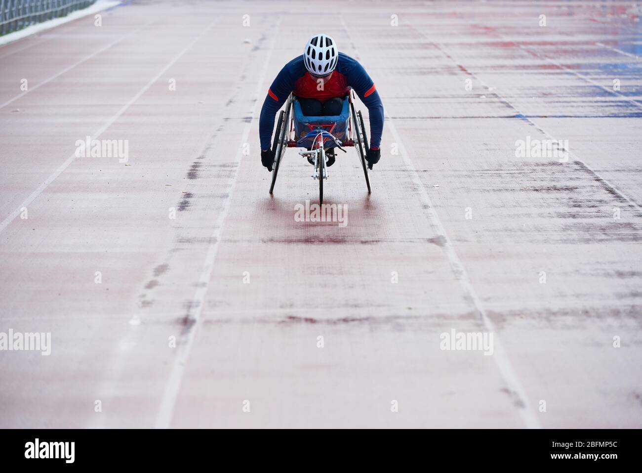 Wheelchair athletics. Paralympic champion in sport wheelchair approaching finish line while having racing competition at outdoor track and field stadi Stock Photo