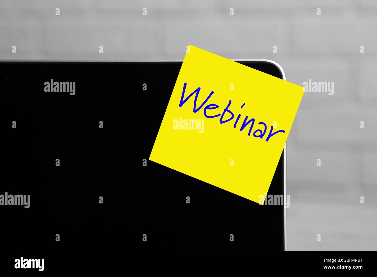 Webinar written on sticky note on laptop screen Stock Photo