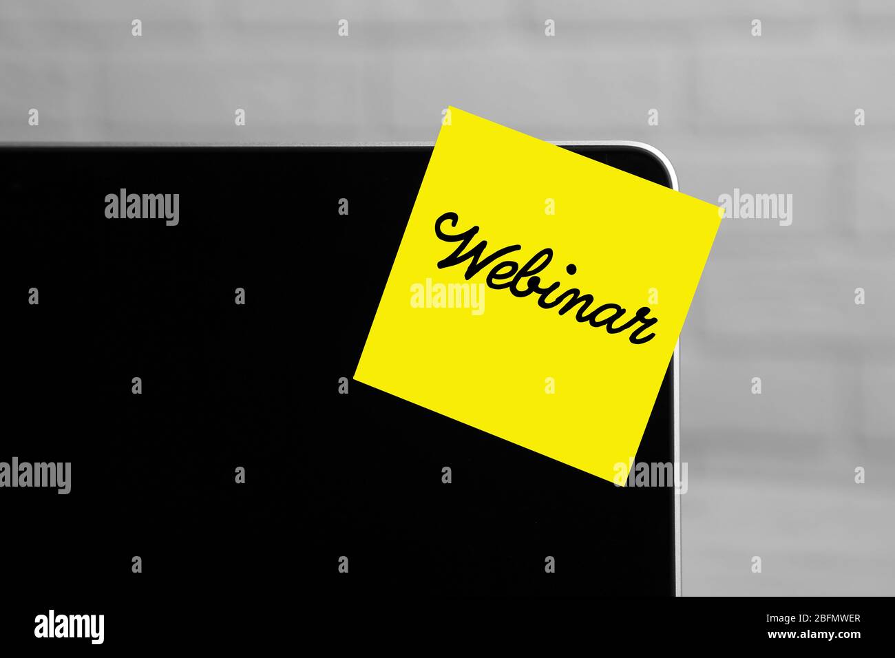 Webinar written on sticky note on laptop screen Stock Photo