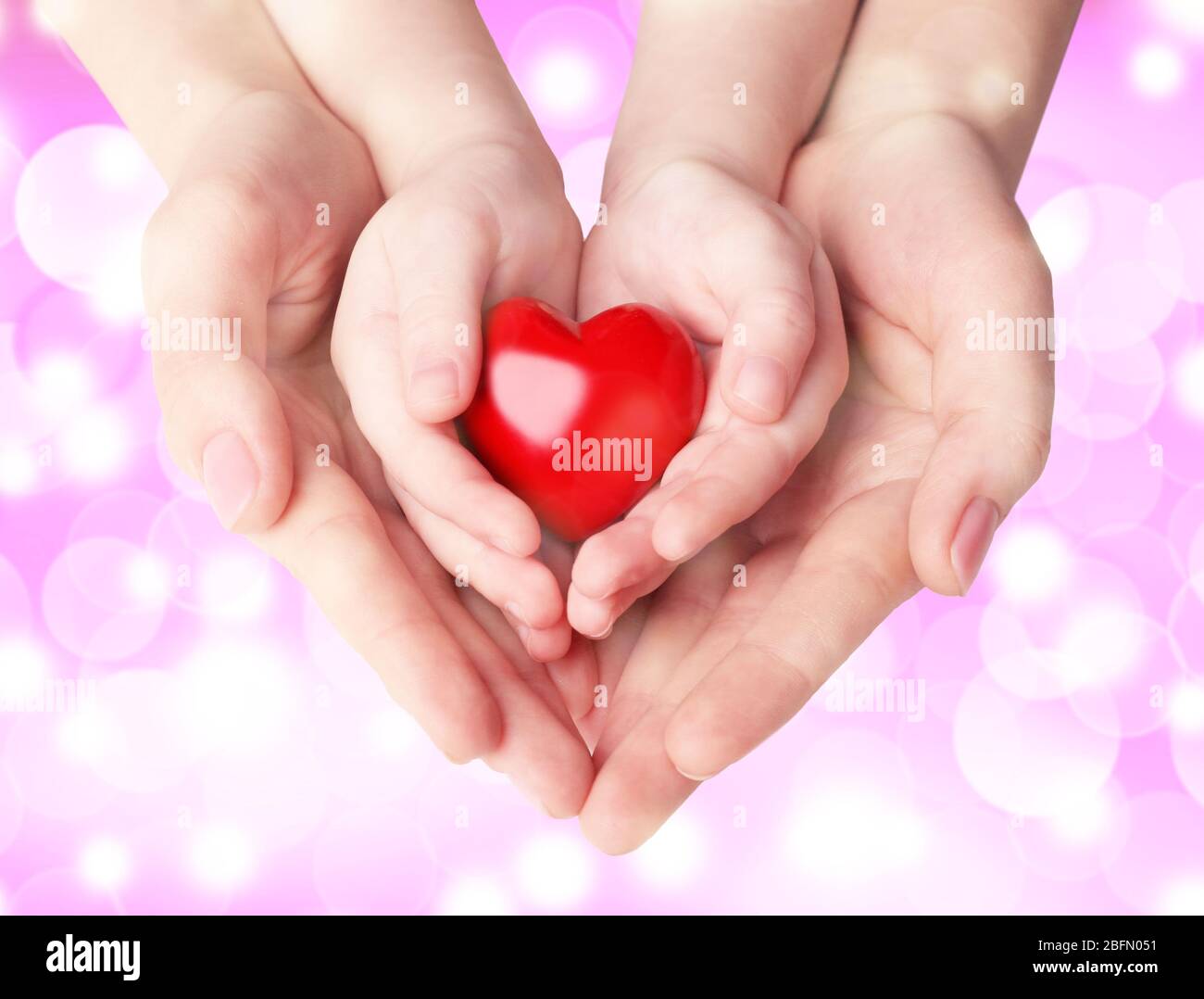 Female and child hands holding red heart on blurred background. Family, love  and health care concept Stock Photo - Alamy
