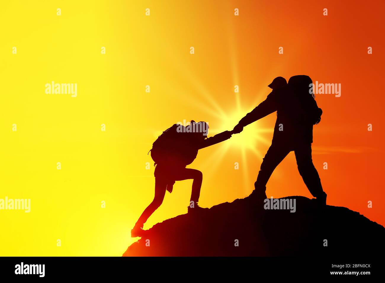 Helping hands with sunlight between two climbers Stock Photo