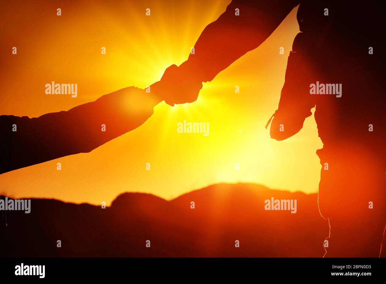 Helping hands with sunlight between two climbers Stock Photo