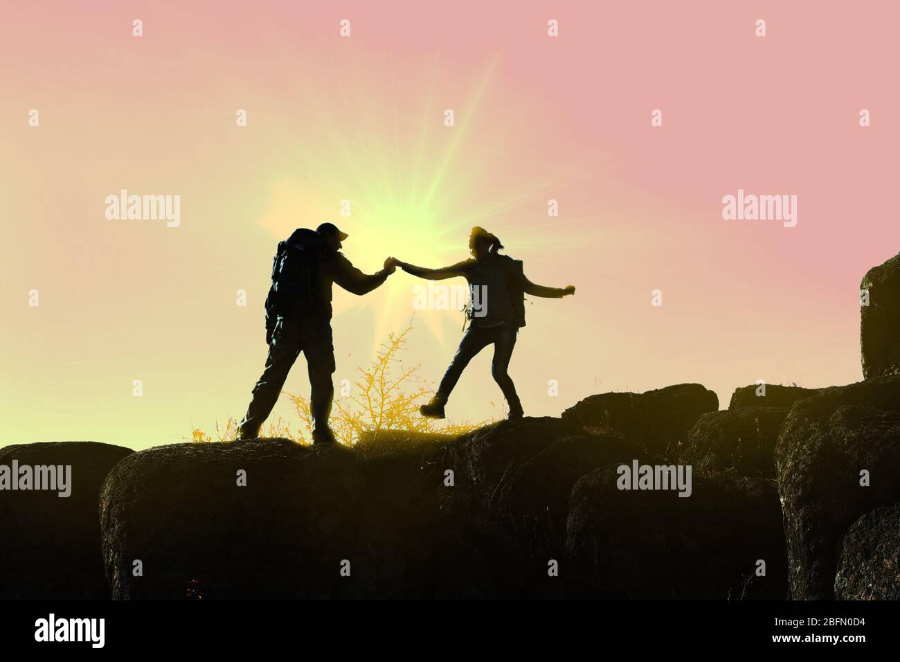 Helping hands with sunlight between two climbers Stock Photo