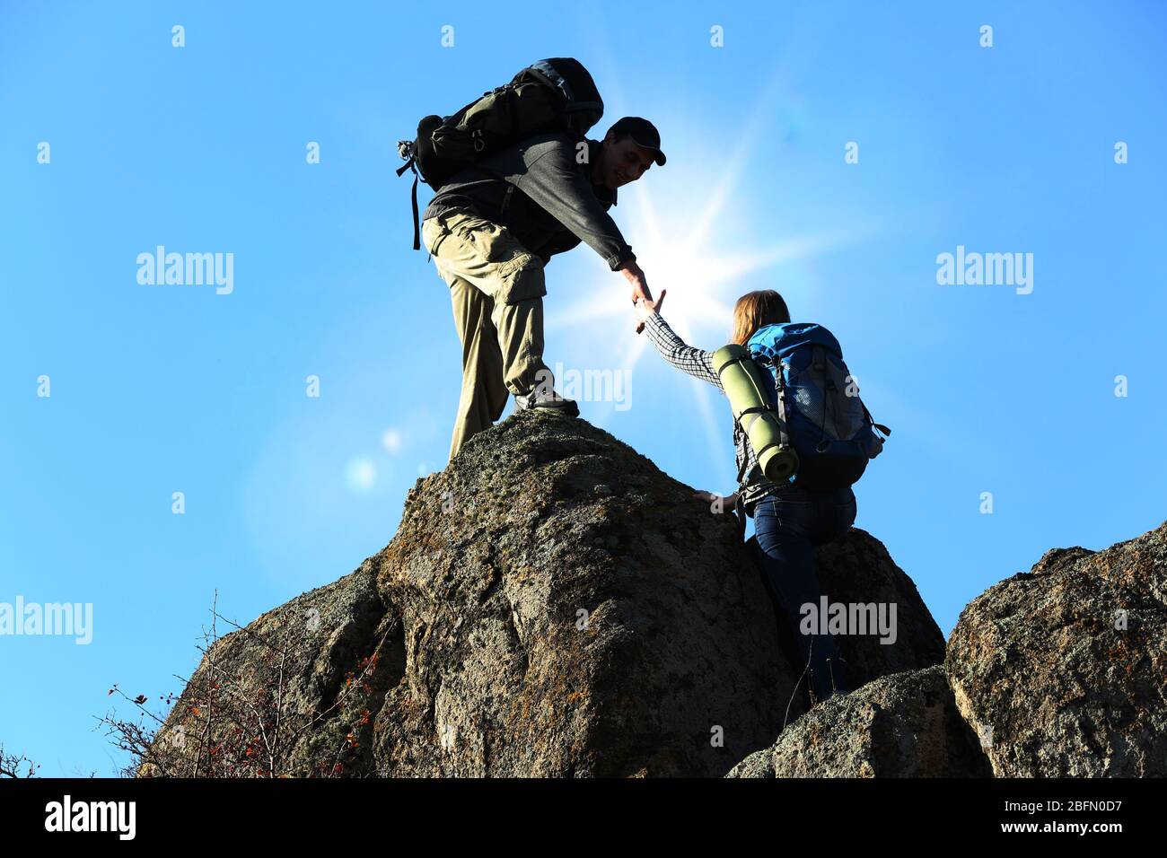 Helping hands with sunlight between two climbers Stock Photo