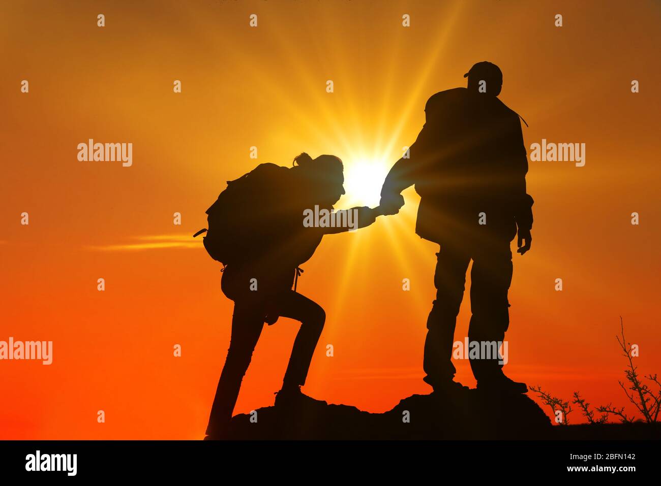 Helping hands with sunlight between two climbers Stock Photo
