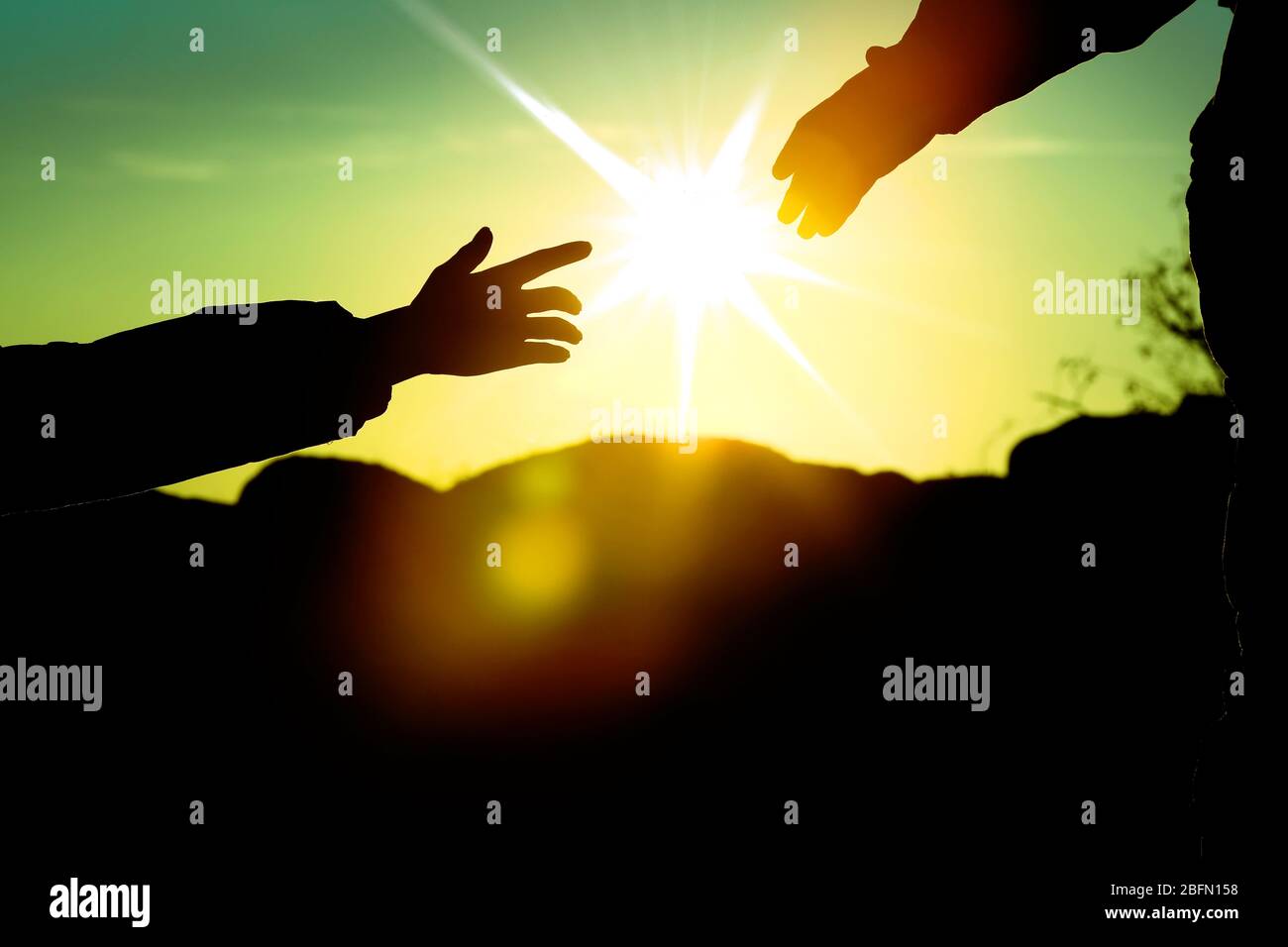 Helping hands with sunlight between two climbers Stock Photo