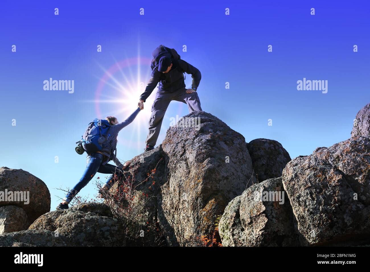 Helping hands with sunlight between two climbers Stock Photo