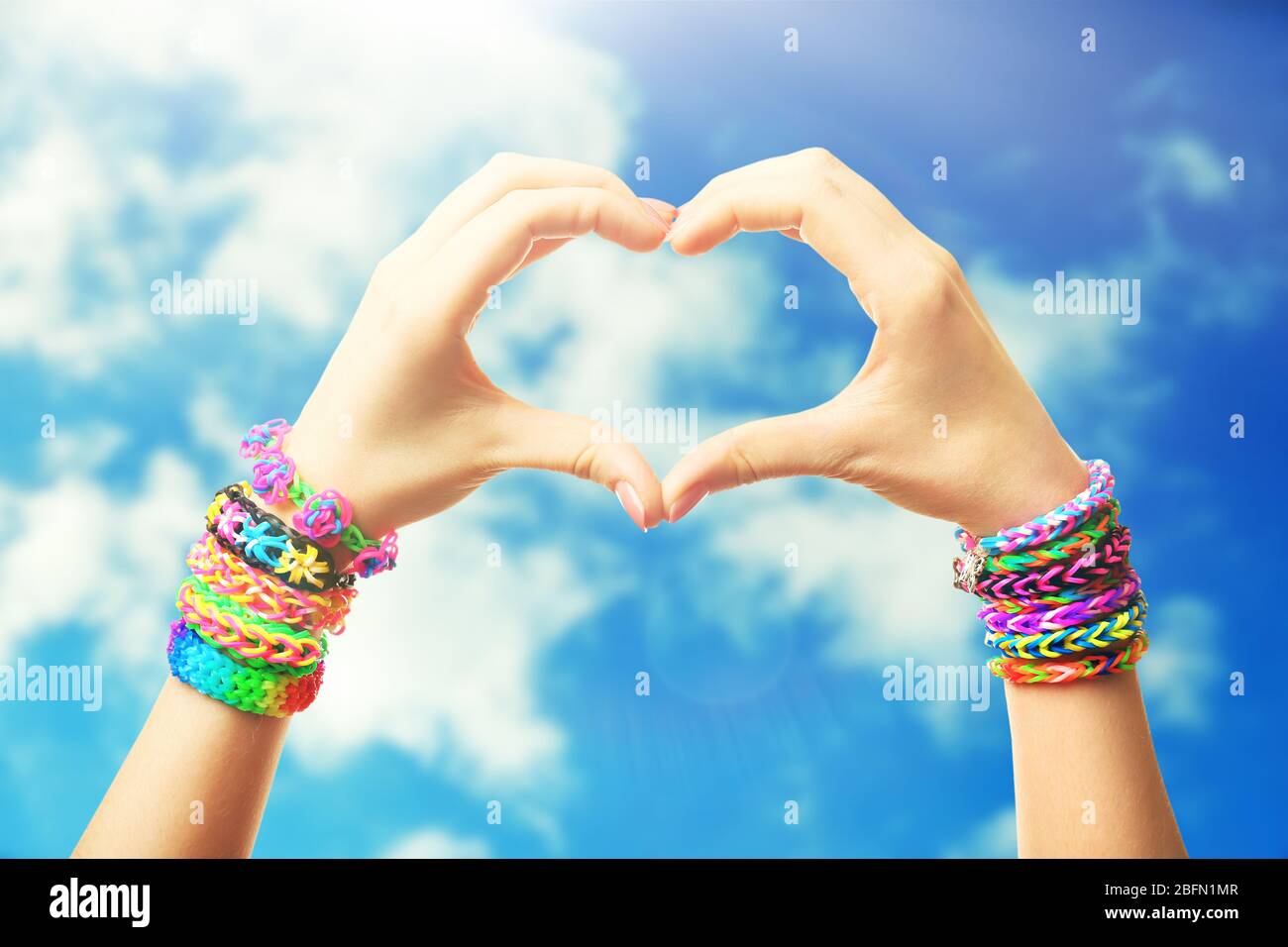 Female hands in shape of heart, on blue sky background Stock Photo - Alamy