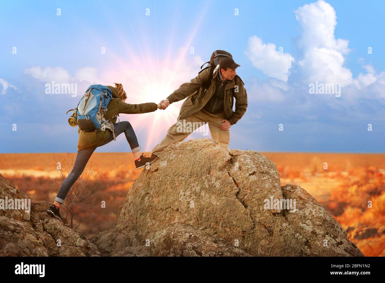 Helping hands with sunlight between two climbers Stock Photo