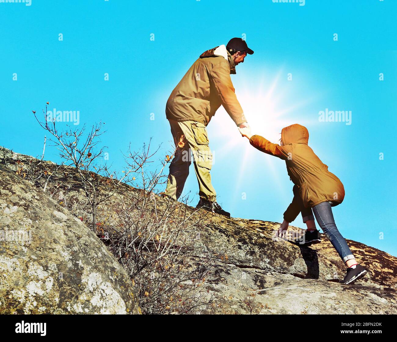 Helping hands with sunlight between two climbers Stock Photo
