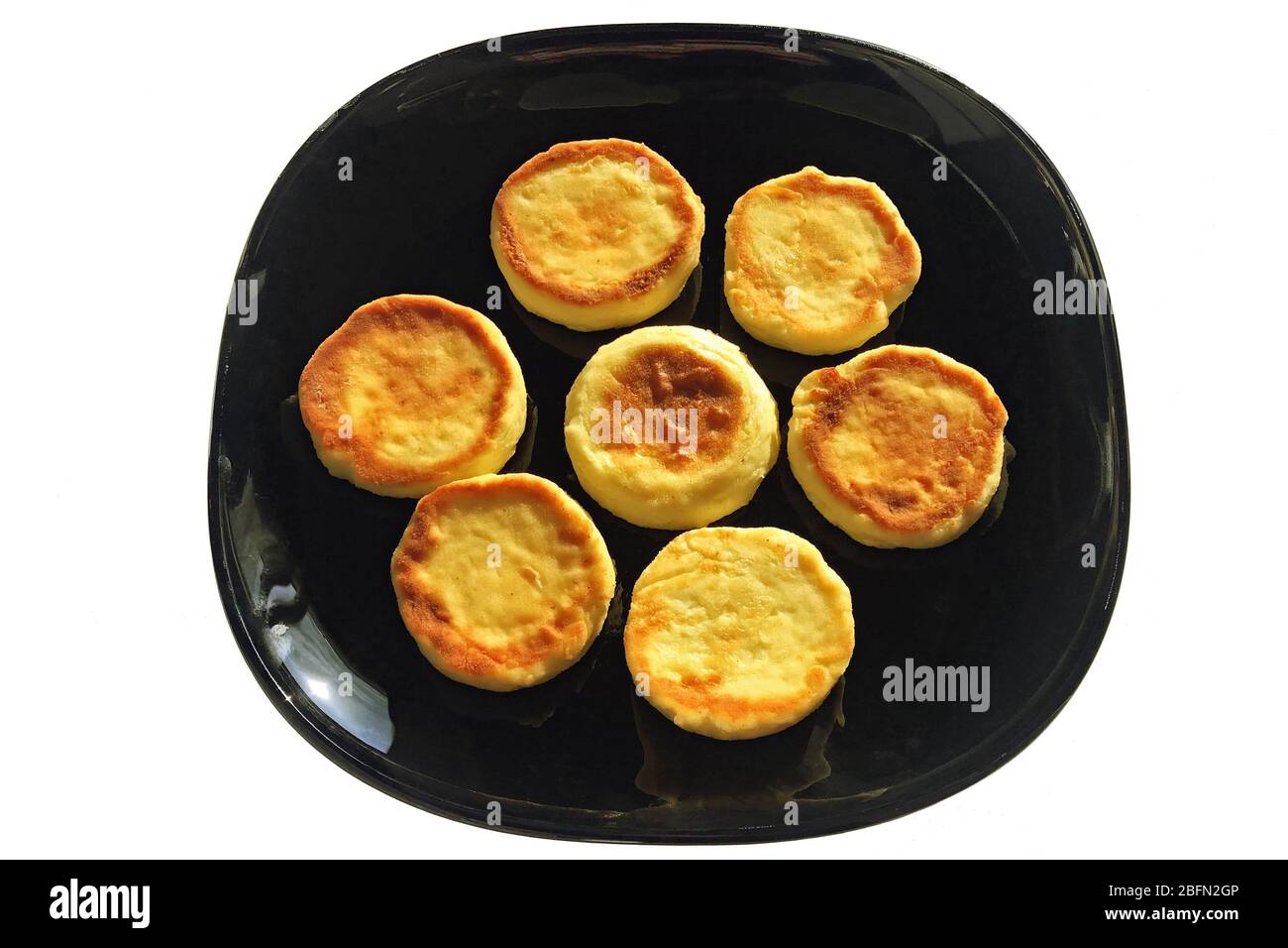 Delicious rosy fried cheesecakes on a dark dish, isolated on a white background. Stock Photo